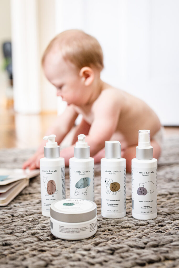 Baby with skin care products in front